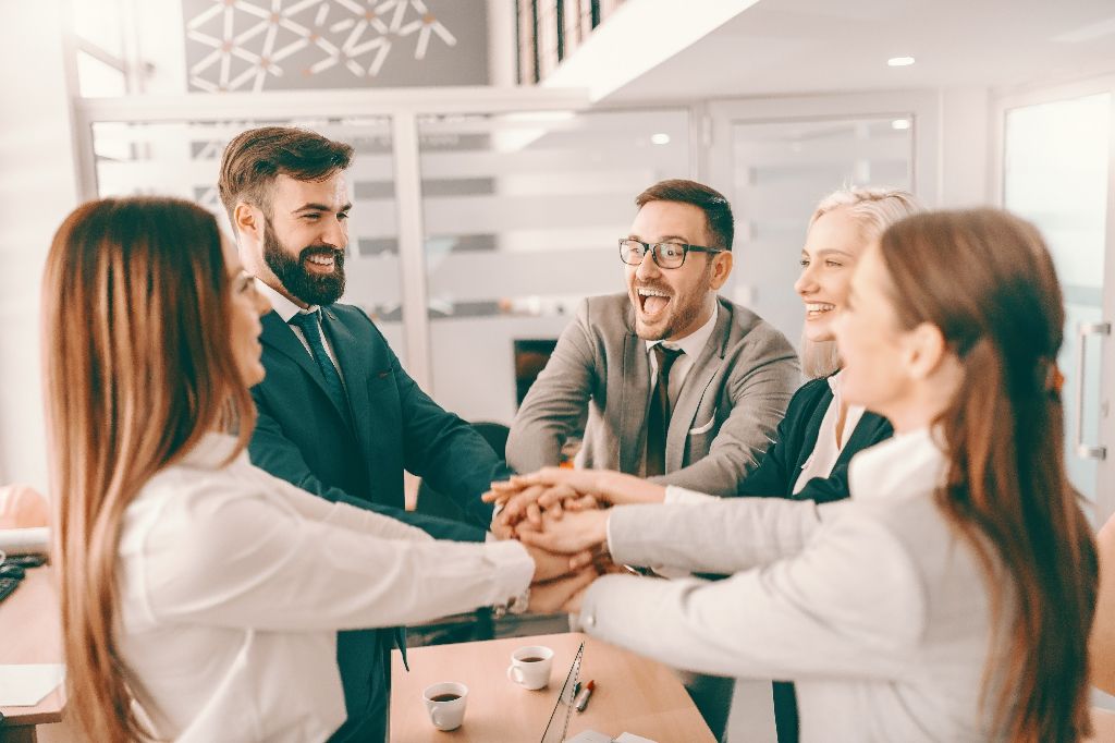 Group of cheerful corporate businesspeople in formal wear stacki Group of cheerful corporate businesspeople in formal wear stacking hands at meeting in boardroom. Catch your people doing something right and let them know you appreciate it.