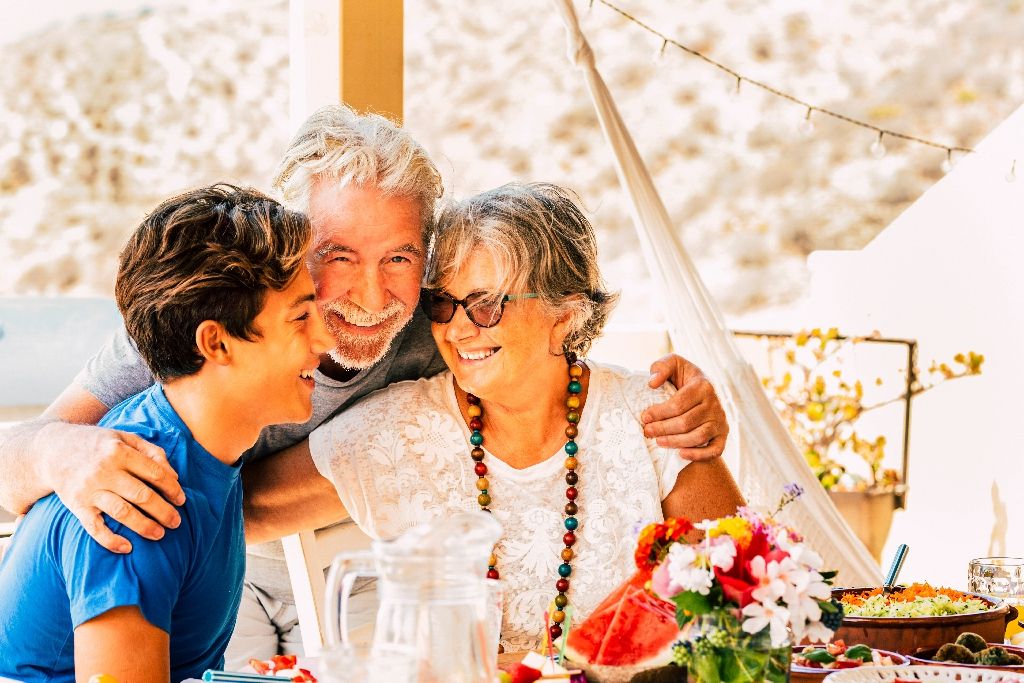 Cheerful happy family celebrate together at lunch hugging and smiling - mixed generations ages with grandfathers and caucasian teenager grandson - social contact for healthy people outdoor
