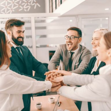 Group of cheerful corporate businesspeople in formal wear stacking hands at meeting in boardroom. Catch your people doing something right and let them know you appreciate it.